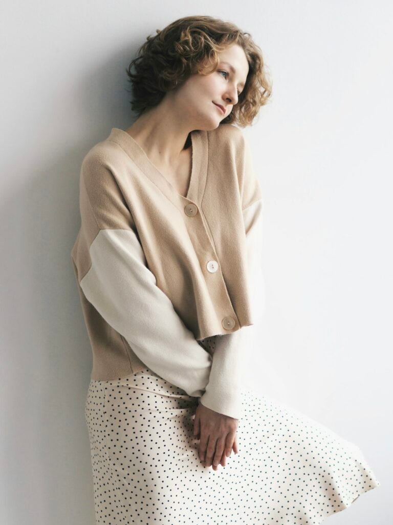 Cardigan en maille beige porté sur une jupe claire